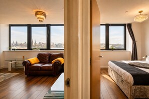A modern hotel room with a city view, a leather sofa, a bed, and a glass partition. - Spacious Liverpool City Centre Apartment with View Managed by Sidemersey Livings (Liverpool)