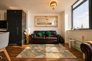 A modern living room with a leather sofa, a large mirror, and a city view. - Spacious Liverpool City Centre Apartment with View Managed by Sidemersey Livings (Liverpool)