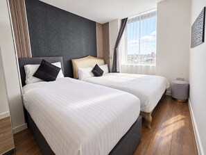 Une chambre d’hôtel avec deux lits, une grande fenêtre et une vue sur la ville.