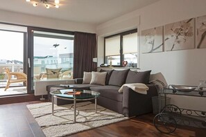Sala de estar moderna com sofá, mesa de centro de vidro e vista através de uma porta de correr.