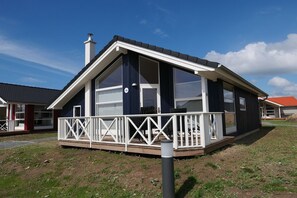 Una casa a un piano con un balcone, una canna fumaria e un cartello con il numero 16.