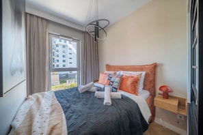 Una camera da letto con un letto grande, un comodino, una lampada e vista su un edificio.