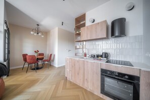 Una cucina moderna con forno integrato, un'area pranzo con tavolo e sedie, e una lampada a sospensione.