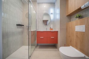 A modern bathroom with a glass shower enclosure, a wooden vanity with a mirror, and a white toilet. - Kierbedzia Comfort Stay, Mokotów, Warsaw (Warszawa)