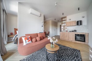 Un soggiorno moderno con un divano, un tavolino da caffè e un angolo cottura con pensili ed elettrodomestici.
