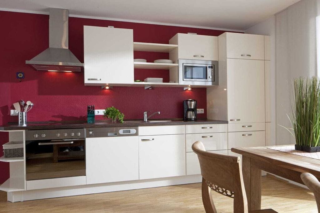 A modern kitchen with white cabinets, a stainless steel range hood, a microwave, and a coffee maker.