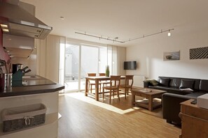 Eine moderne Küche mit Essbereich, einer Couch und einem Fernseher.