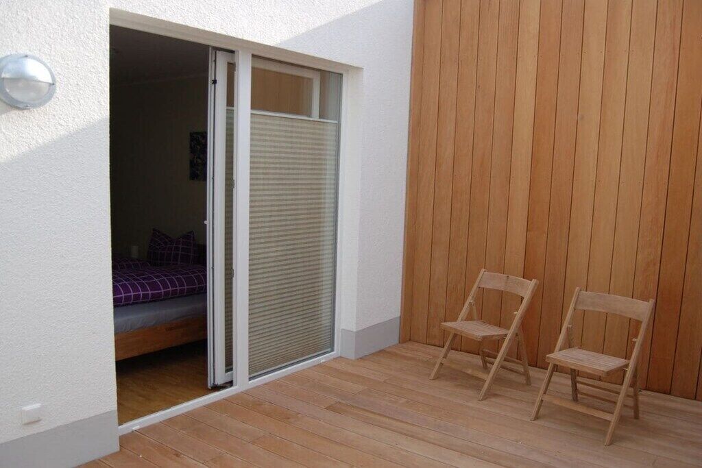 Une pièce comprenant un lit, une porte coulissante et deux chaises en bois.