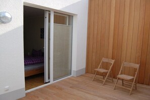 A room with a bed, a sliding door, and two wooden chairs. - Holiday apartment in Norderney with Wi-Fi (Norderney)