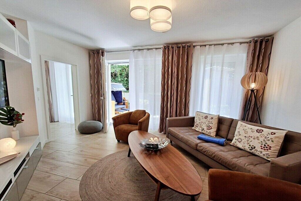 Ein modernes Wohnzimmer mit einer Couch, einem Sessel, einem Couchtisch, einem Fernseher und einer Lampe.