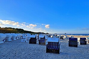 Accommodatie aan het strand met rijen vakantiewoningen, een zandstrand en een heldere lucht.