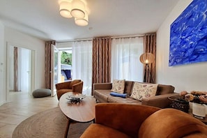 A modern living room with a sofa, armchairs, a coffee table, and a dining area. - Villa Bettina Apartment 03 (Heringsdorf (Seebad))