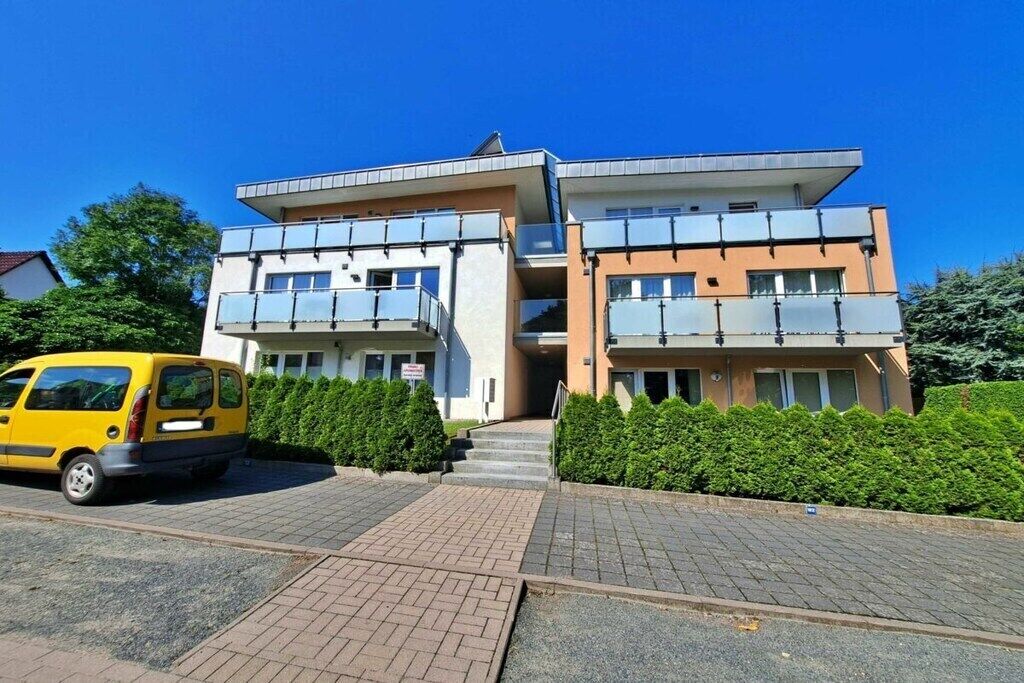 Un edificio de varios pisos con un estacionamiento y una furgoneta amarilla estacionada frente a él.