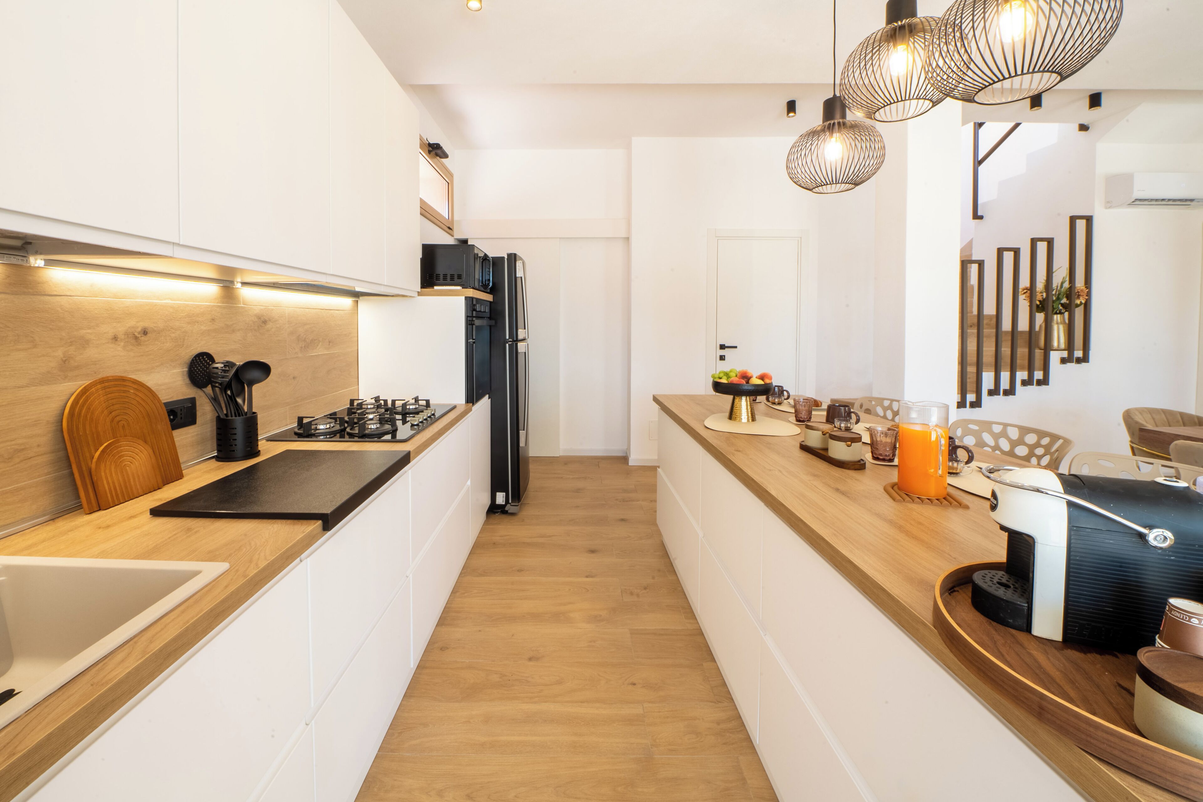 Una cocina moderna con armarios blancos, encimera de madera y estufa a gas integrada.