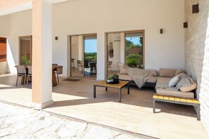 Un espacio al aire libre moderno con sofá, mesa de centro y mesa de comedor.