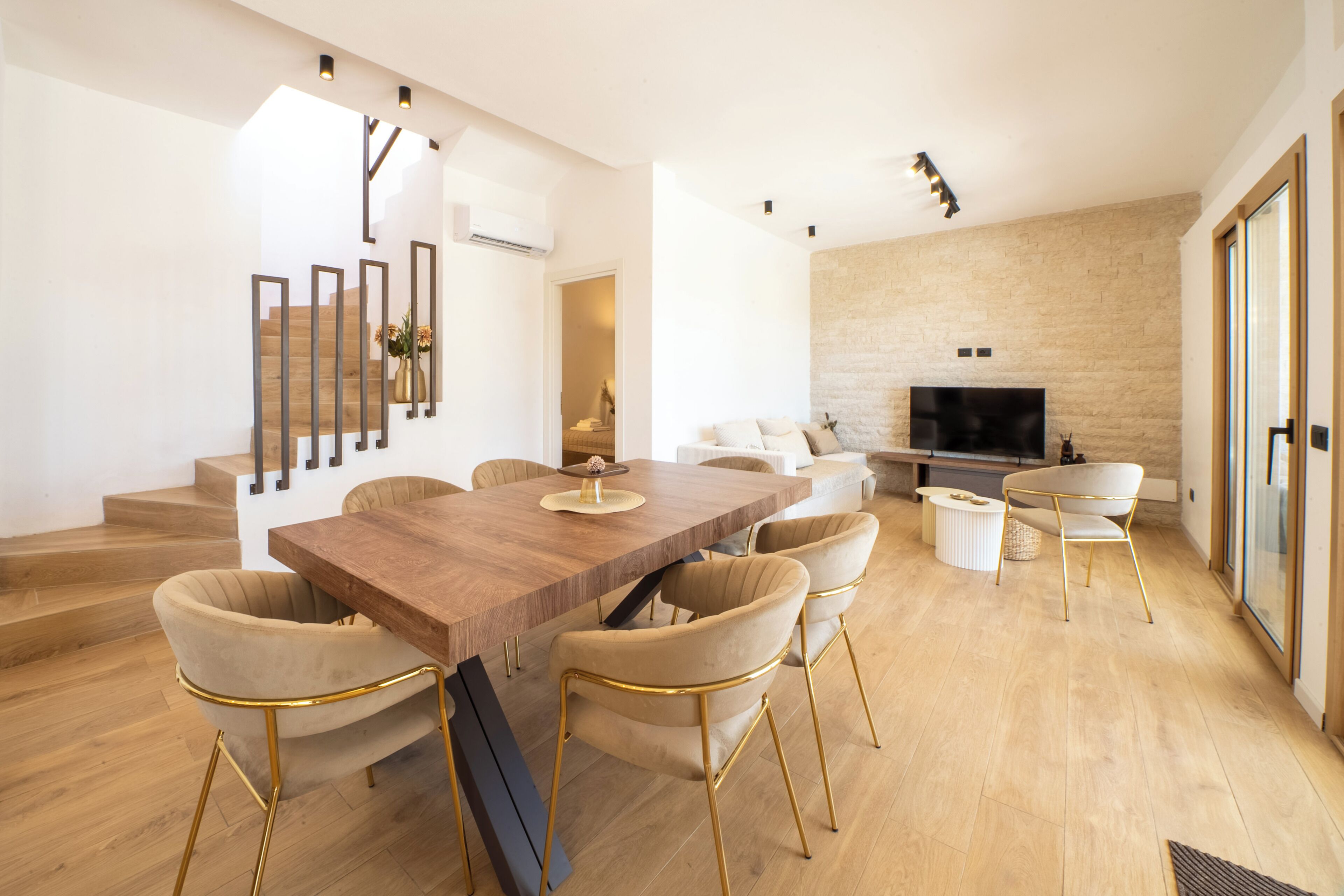 Un salon moderne avec une table à manger en bois, des sièges confortables, une cheminée et un escalier menant à un niveau supérieur.