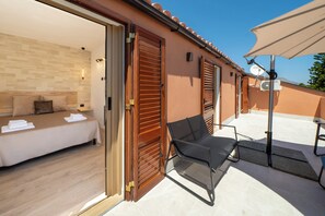 Una habitación de hotel con una cama, una silla y una puerta abierta que da a un balcón.