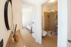 Un baño moderno con ducha envuelta en vidrio, inodoro blanco y lavamanos.