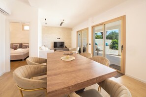 Ein modernes Wohnzimmer mit einem Holzesstisch, bequemen Sitzgelegenheiten, einem Flachbildfernseher und einer Wand aus Naturstein.