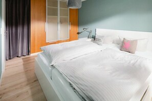 Une chambre à coucher avec un lit, une table de chevet, une lampe et une fenêtre avec des rideaux.