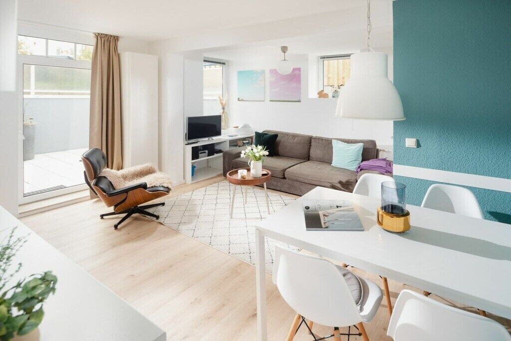 Ein modernes Wohnzimmer mit einer Couch, einem Couchtisch, einem Fernseher und einem Essbereich mit Stühlen und Tisch.