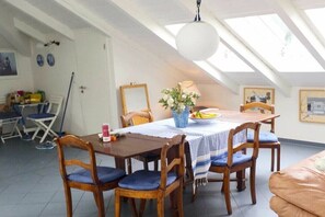 Een eethoek met een tafel en stoelen, een vaas met bloemen en een plafondventilator.