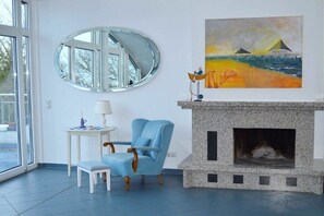A room with a fireplace, a blue armchair, a small table with a lamp, and a large painting on the wall. - in the lake park "Heringsdorf" (Heringsdorf (Seebad))