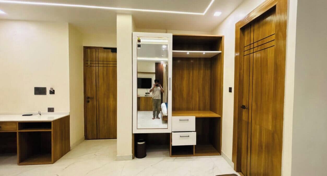 Una habitación con un armario de madera, un escritorio y un espejo.
