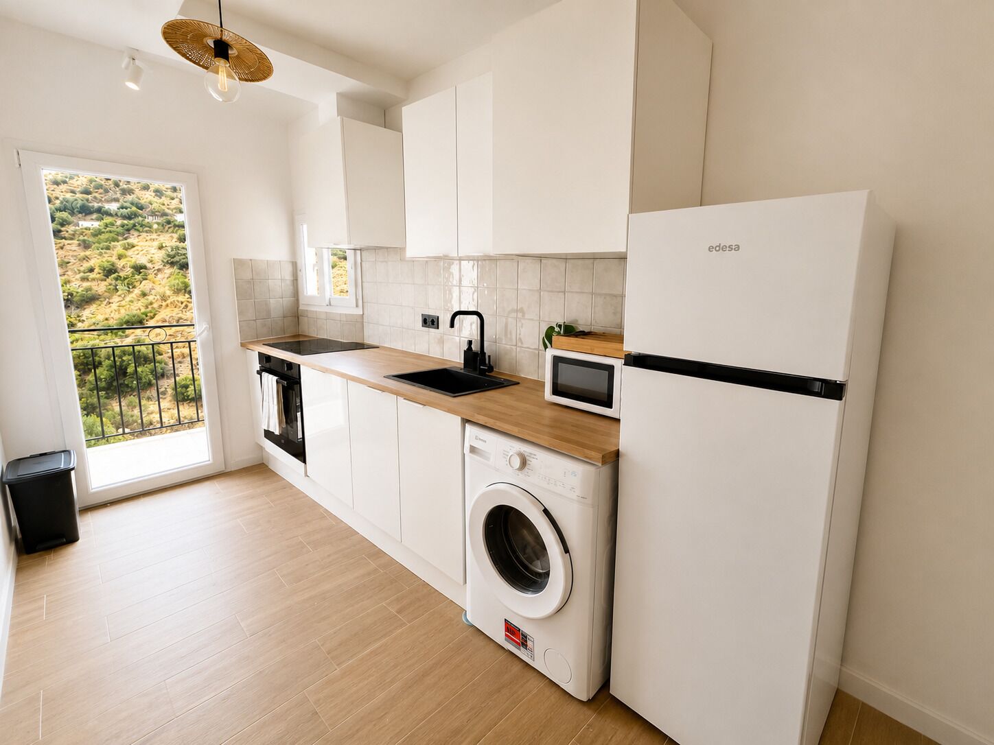 A modern kitchen with a washing machine, a microwave, and a refrigerator.