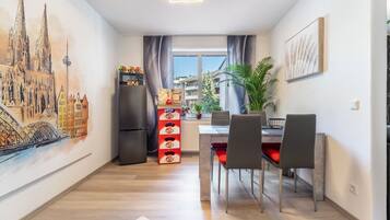 A modern kitchen with a dining area, a refrigerator, and a window with a view of buildings.