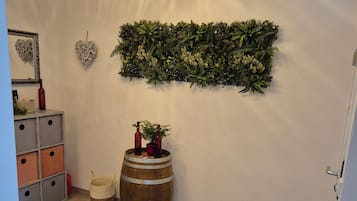 A room with a wooden barrel, a red rug, a wall-mounted plant, and a mirror with a heart-shaped decoration.