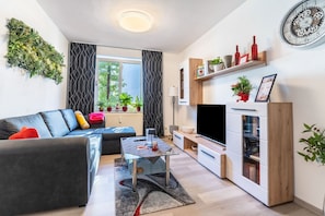 Una sala de estar moderna con sofá, mesa de centro, mueble para la televisión y plantas decorativas.
