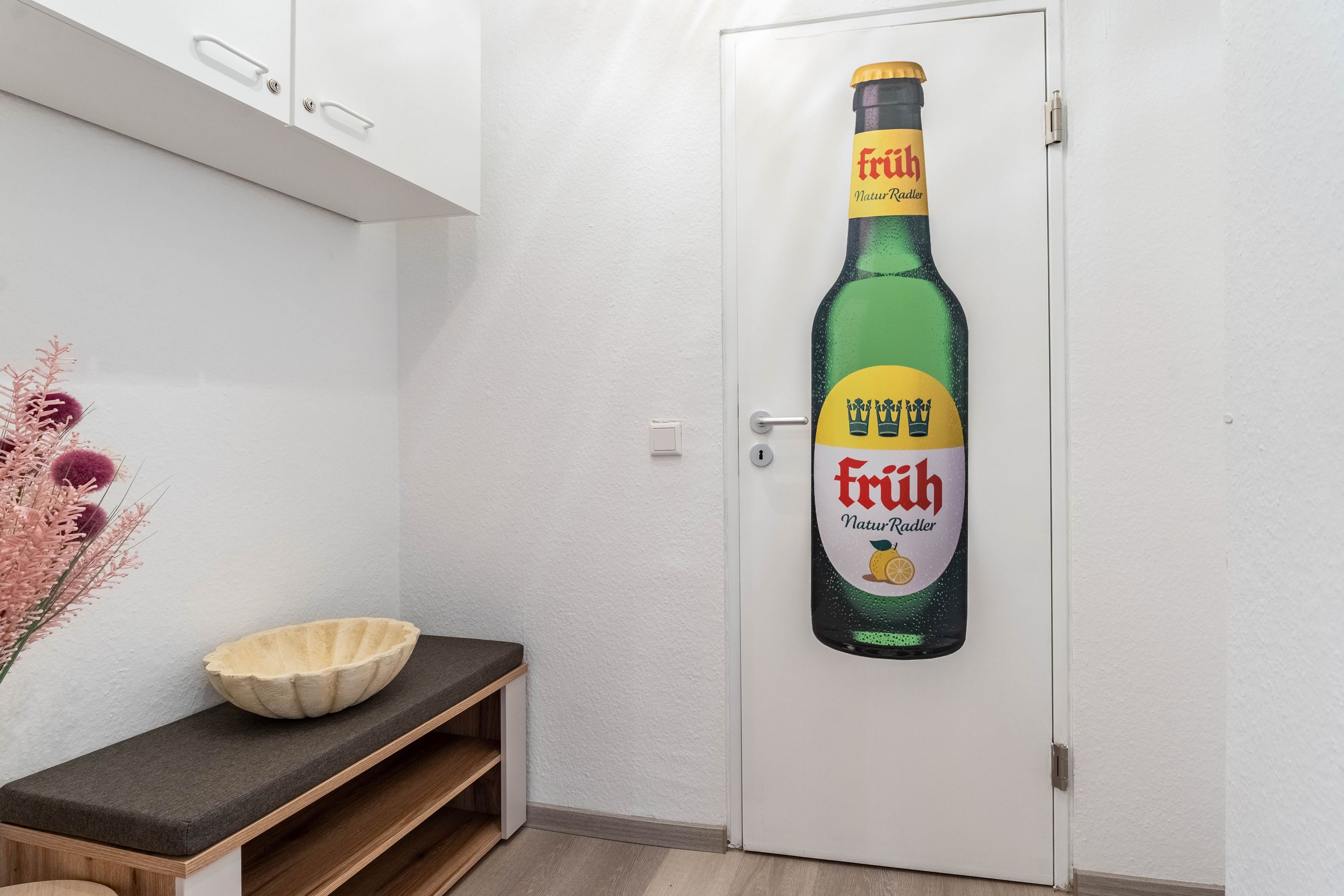 Una puerta con una botella de cerveza Fruh NaturRadler usada como aldaba.