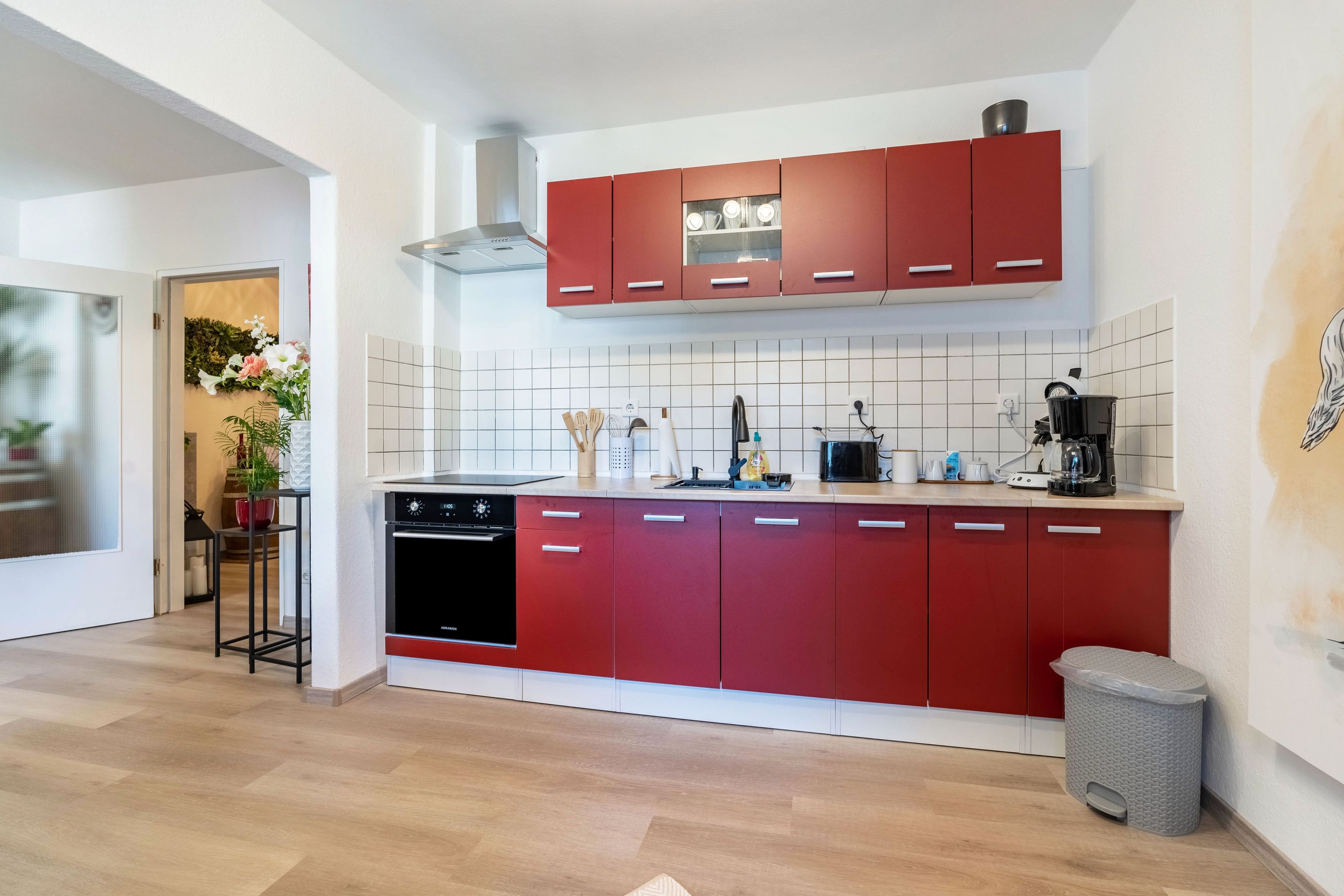 A modern kitchen with red cabinets, a dishwasher, and a coffee machine.