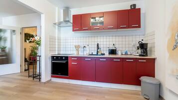 A modern kitchen with red cabinets, a dishwasher, and a coffee machine.