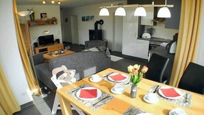Una sala de estar moderna con comedor, un sofá, una mesa de centro y una cocina al fondo.
