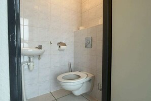 A small, clean bathroom with a toilet, a sink, and a toilet paper holder. - Wijk de Brabander 58 (Cadzand)
