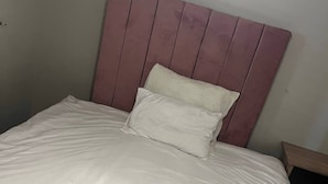 Una cama con cabecera, almohada y manta.