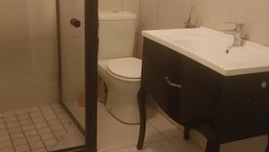 Un baño con inodoro, lavabo y zona de ducha.