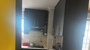 Una cocina compacta con armarios oscuros, una estufa y una pequeña encimera.