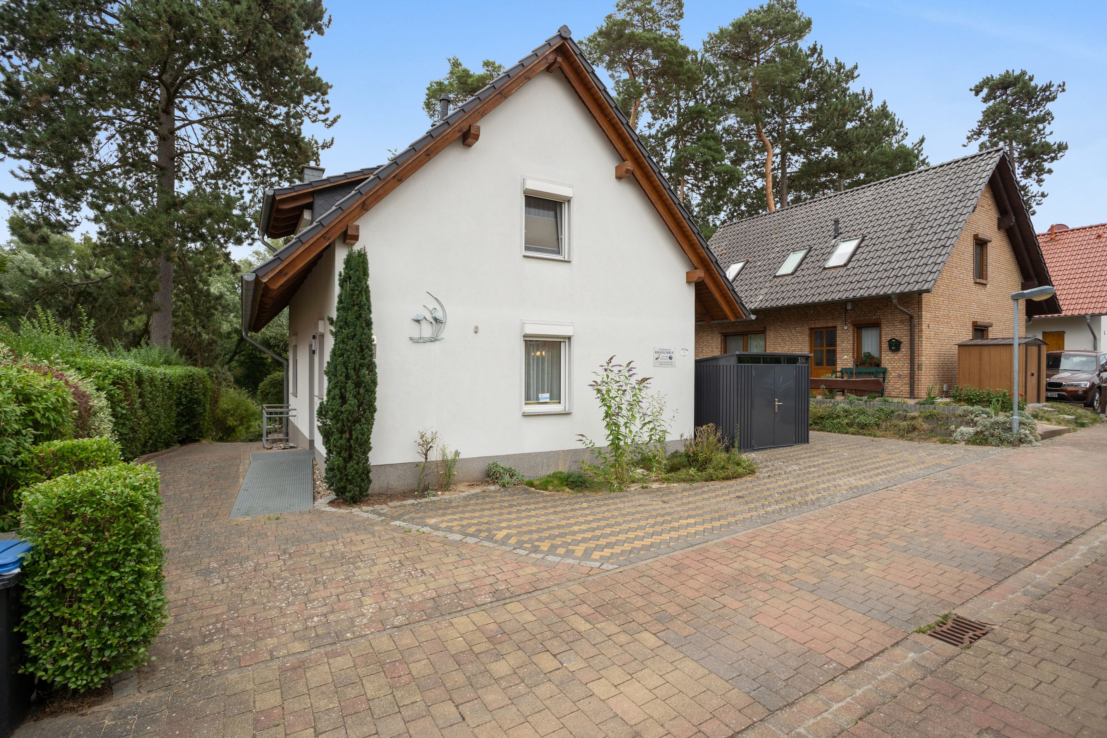 Ein zweistöckiges Haus mit geneigtem Dach, einer Veranda und einer gepflasterten Auffahrt.
