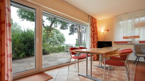 Ein moderner Essbereich mit Tisch, Stühlen, einem Fernseher und Blick ins Freie.