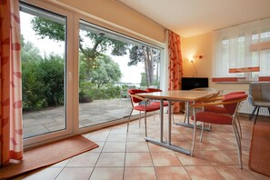 A modern dining area with a table and chairs, a television, and a view of the outdoors. - Apartment 'Haus 3 Eg' with Sea View, Private Terrace and Wi-Fi (Röbel)