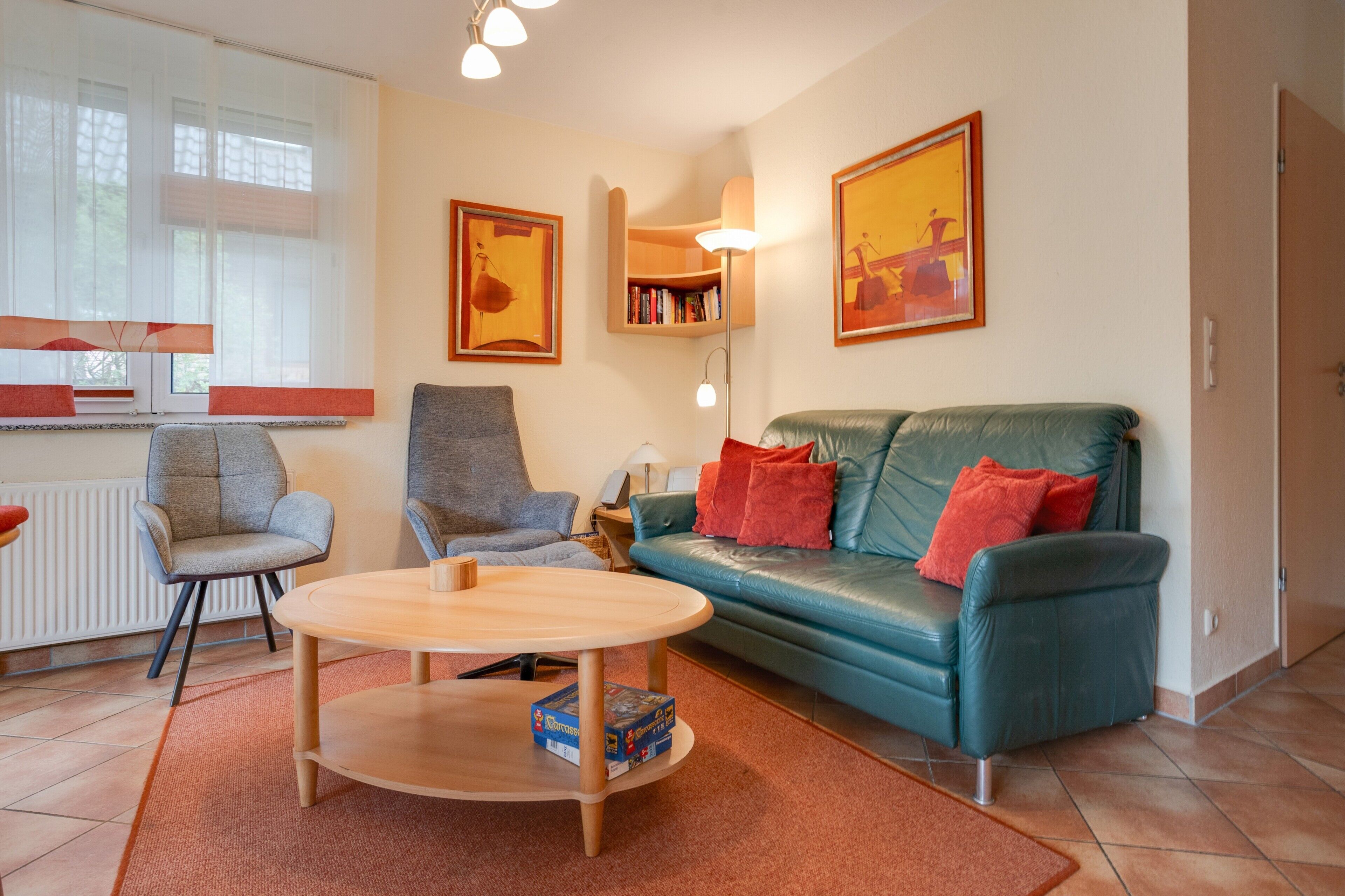 Ein Wohnzimmer mit einer Couch, Sesseln, einem Couchtisch und einem Bücherregal.