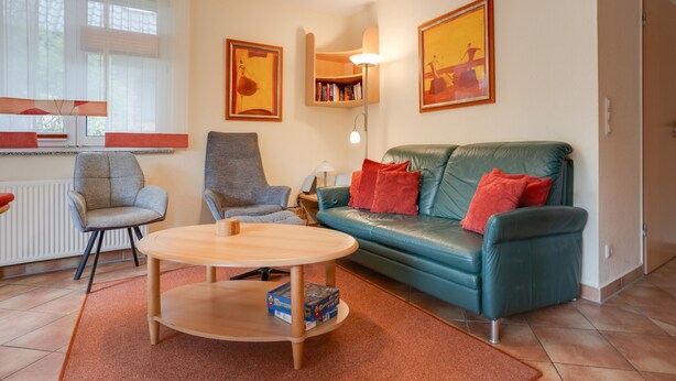 Ein Wohnzimmer mit einer Couch, Sesseln, einem Couchtisch und einem Bücherregal.