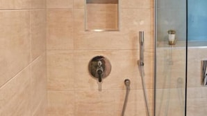A modern bathroom with a glass shower enclosure, a handheld showerhead, and a wall-mounted faucet. - Lordington Park (Chichester)