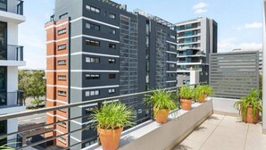 Un moderno edificio de apartamentos con varios pisos, balcones y plantas en macetas.