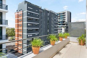 Ein modernes Mehrfamilienhaus mit mehreren Etagen, Balkonen und Topfpflanzen.