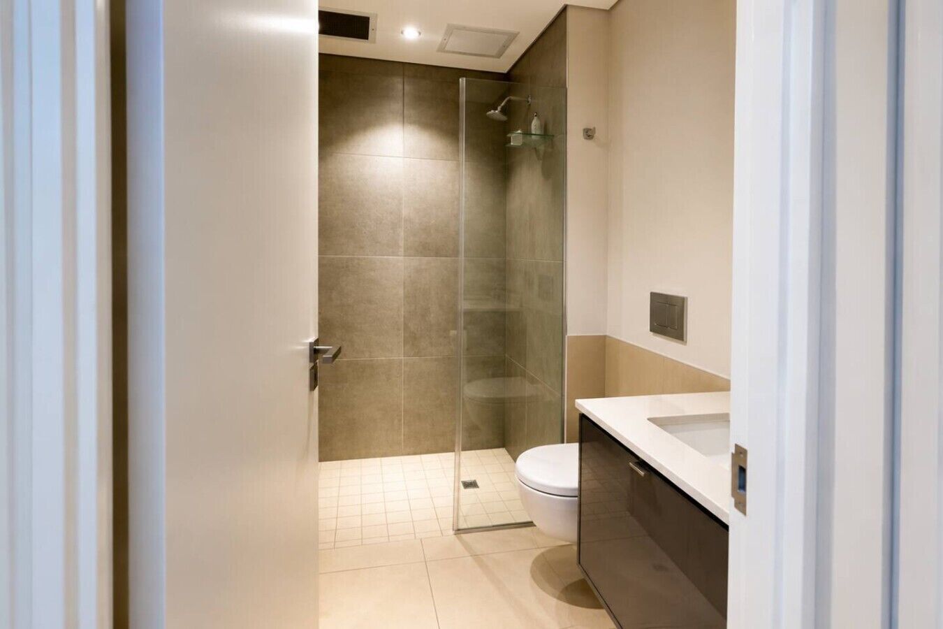 A modern bathroom with a glass-enclosed shower, a toilet, and a vanity with a sink.
