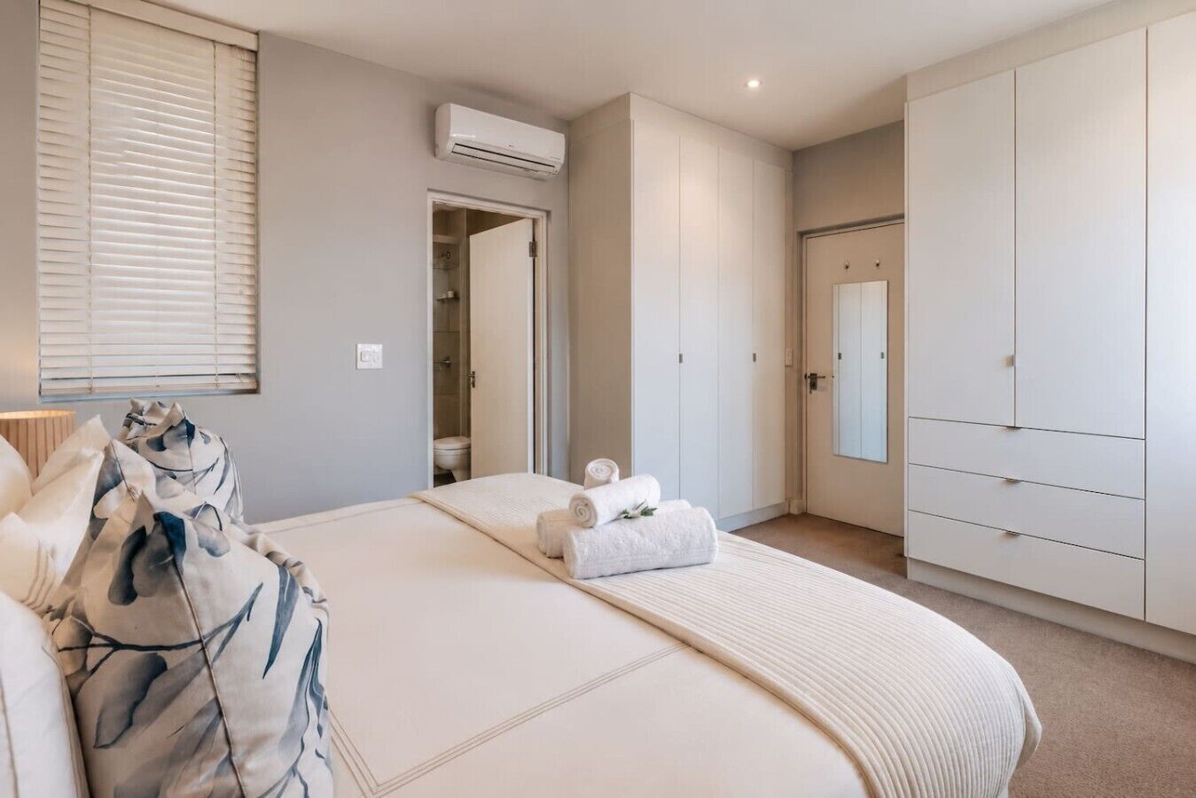 A bedroom with a bed, a wardrobe, and a bathroom door.